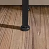 Close-up of the black metal leg of a table with a black plastic foot on a wooden floor. Podgląd zdjęcia produktu