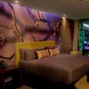 A bedroom with a large mural on the wall and a bed. Voir les images du produit