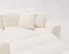 A close-up view of a cream-colored sectional sofa with plush, tufted cushions and two throw pillows. Náhled obrázku produktu