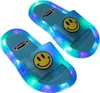 Paar blaue LED-Rutschensandalen mit gelben Smiley-Gesichtern auf den Riemen, von oben gesehen Náhled obrázku produktu