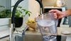 A person is filling a water filter pitcher under a kitchen faucet. Náhľad obrázku produktu