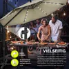 People enjoying a meal outdoors under a large umbrella with lights. Anteprima dell’immagine prodotto