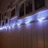 A string of starburst-shaped LED lights is draped along a white wall, with framed pictures hanging above. Produktbild-Vorschau