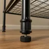 A close-up view of the adjustable foot of a black metal shelving unit. Podgląd zdjęcia produktu