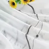 A close-up view of a white sheer curtain with embroidered details and a subtle floral pattern. Sunflowers are visible in the upper left corner. Produktbild-Vorschau
