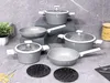 A set of grey cookware is displayed on a grey, textured surface, with some pasta and a plant in the background. Podgląd zdjęcia produktu