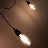 Two pendant light bulbs hanging from black cords against a brown background. Produktbild-Vorschau