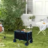 A garden scene with a folding wagon filled with gardening tools and supplies, a hose reel, and outdoor furniture. Produktbild-Vorschau
