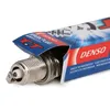 A close-up shot of a Denso spark plug partially emerging from its packaging. Produktbild-Vorschau