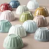 A collection of colorful ceramic bowls arranged on a pink surface. Produktbild-Vorschau