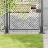 A close-up view of a metal fence post base with green grass in the foreground and a chain-link fence in the background. Produktbild-Vorschau