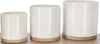 Three white ceramic planters of varying sizes with bamboo bases are displayed on a neutral surface against a white background. Produktbild-Vorschau