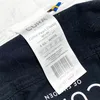 A close-up of a product label attached to a black fabric. Podgląd zdjęcia produktu
