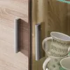 Close-up view of cabinet doors with handles and stacked mugs. Produktbild-Vorschau