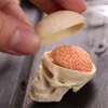 A hand is holding the lid of a miniature skull model, revealing a miniature brain inside. Anteprima dell’immagine prodotto