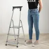 A person stands next to a silver step ladder with three steps. Podgląd zdjęcia produktu