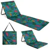 A foldable beach mat with a tropical fruit and leaf pattern, shown in multiple configurations. Produktbild-Vorschau