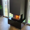 A modern fireplace with a fire burning inside, set in a room with large windows and a wooden floor. Anteprima dell’immagine prodotto