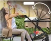 A woman is holding a baby while sitting on a bench next to a stroller. Produktbild-Vorschau