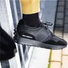 A close-up shot of a person's foot wearing a black New Balance sneaker, resting on a metal railing. Anteprima dell’immagine prodotto