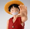 A close-up shot of an action figure of Monkey D. Luffy from One Piece, wearing his signature straw hat and red vest, with his hand extended towards the camera. Náhled obrázku produktu