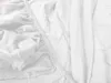 A close-up view of a white fitted sheet, showing the elasticized edge and fabric texture. Náhľad obrázku produktu
