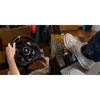 A person's hands are shown operating a racing steering wheel and pedals, suggesting a gaming or simulation setup. Podgląd zdjęcia produktu