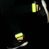 A person's legs wearing black leggings and athletic shoes with reflective ankle bands. Náhled obrázku produktu