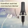 A marketing image showing a flower being blown by wind and a product that is designed to be stable in windy weather. Produktbild-Vorschau