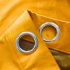 A close-up view of two grommets on a mustard yellow curtain. Produktbild-Vorschau