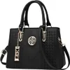 A black handbag with gold-colored hardware and a decorative emblem. Produktbild-Vorschau