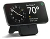 A black smartphone is propped up on a black stand, displaying a clock and weather information. Produktbild-Vorschau