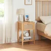 A bedside table next to a bed, with a lamp and picture frame on top. Produktbild-Vorschau