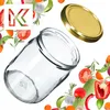 A glass jar and its lid are shown with various vegetables and herbs arranged around them, suggesting preservation or cooking. Voir les images du produit