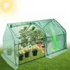 A small greenhouse with plants inside, shown on a grassy lawn under sunlight. Produktbild-Vorschau
