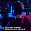 A person wearing headphones and looking at a computer screen in a dimly lit room with colorful lighting. Produktbild-Vorschau