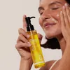 A woman is applying cleansing oil to her face. Produktbild-Vorschau