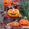 Several carved pumpkins are displayed outdoors among autumn leaves, with a wooden stool and a stone wall in the background. Anteprima dell’immagine prodotto