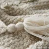A close-up of a knitted blanket with a tassel. Produktbild-Vorschau
