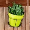 A green plant pot with a black metal holder is mounted on a wooden fence. Podgląd zdjęcia produktu