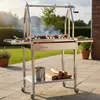 A stainless steel Argentinian charcoal grill with meat cooking on the grate, set up on a patio. Anteprima dell’immagine prodotto
