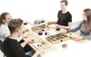 People gathered around a table, enjoying a meal cooked on individual grills. Produktbild-Vorschau