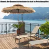 A patio overlooking the sea with a thatched umbrella and lounge chairs. Produktbild-Vorschau