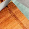 A close-up view of a wooden cutting board with a textured green fabric next to it. Podgląd zdjęcia produktu