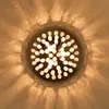 A close-up, top-down view of a crystal chandelier with multiple lights casting a patterned shadow on the wall. Produktbild-Vorschau