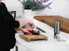 A person is sharpening a knife with a knife sharpener in a kitchen setting. Anteprima dell’immagine prodotto