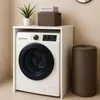 A washing machine with a cabinet on top, a plant, and a laundry hamper next to it, set against a tiled wall. Voir les images du produit