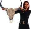 A woman is holding up a decorative bull skull with intricate carvings. Náhled obrázku produktu
