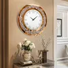 A decorative wall clock is displayed on a wall above a console table with floral arrangements and decorative items. Podgląd zdjęcia produktu