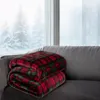 A plaid blanket folded on a couch in front of a snowy window. Produktbild-Vorschau
